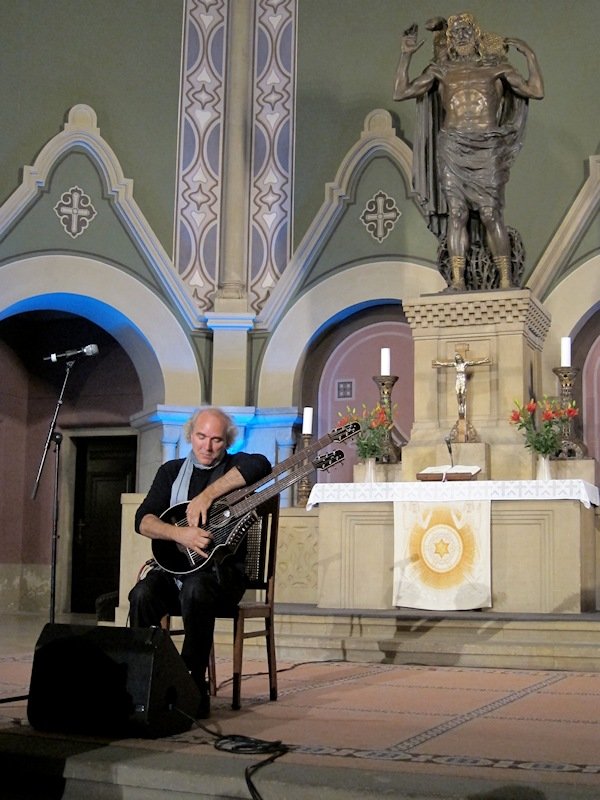 john doan in concert in ancient church playing harp guitar